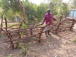 John standing next to his fenced trees in the homestead.
